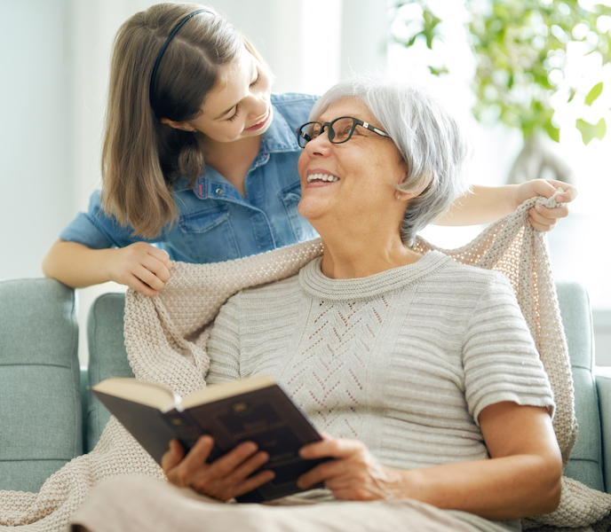 A nice girl and her grandmother enjoy sunny morning. Good time at home.