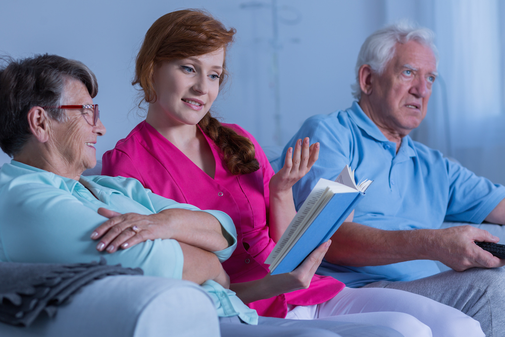 Caregiver reading to elderly woman. Guardianships in Minnesota