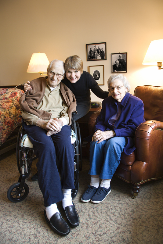 Middle-aged daughter with elderly parents in retirement community center.