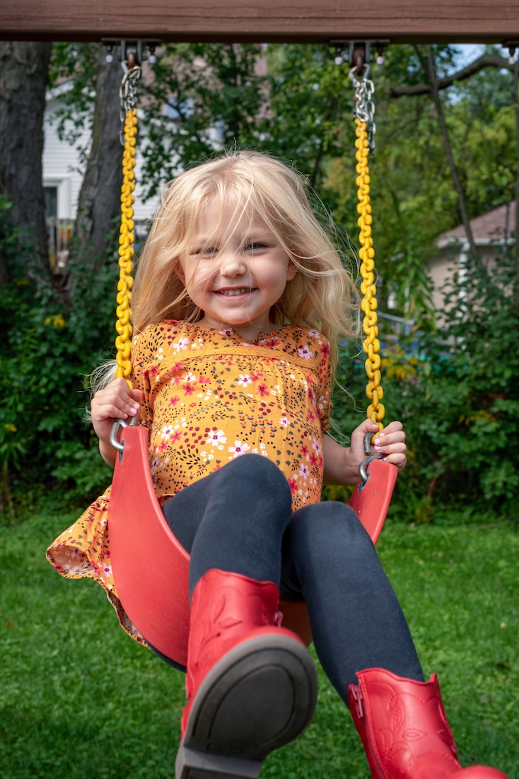 Happy little girl playing on the swing