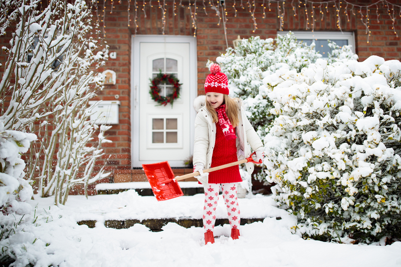 Home in winter. Girl shoveling sidewalk