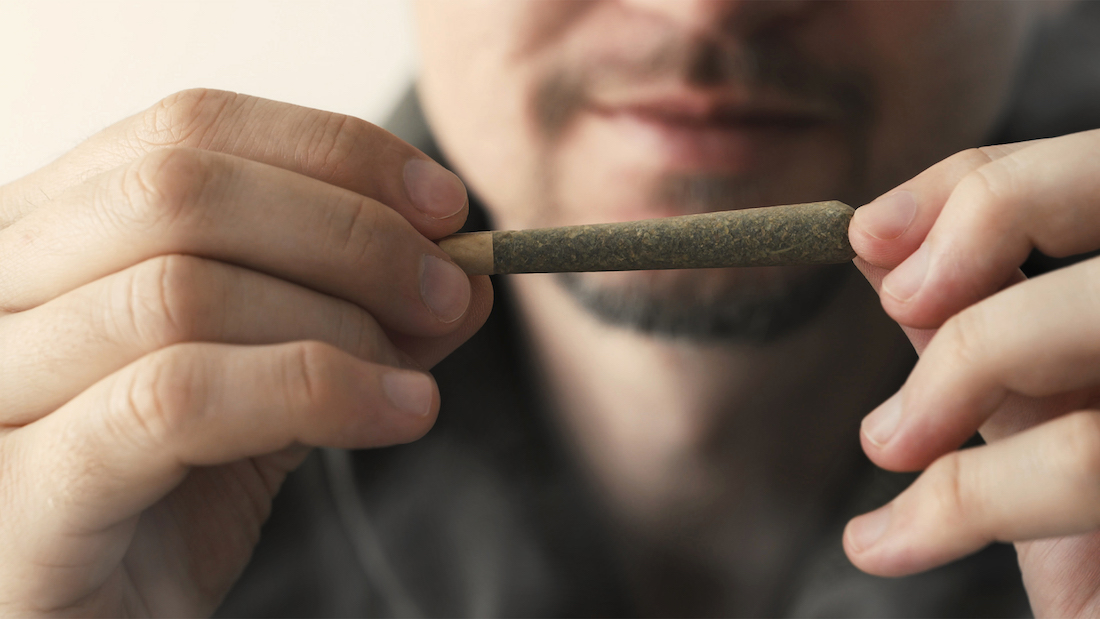 Young man holding marijuana joint in hands