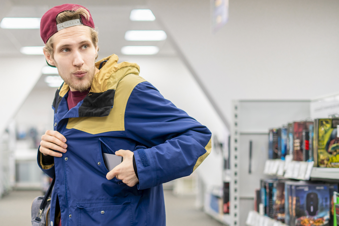 Man stealing cell phone in the shop looking sideways